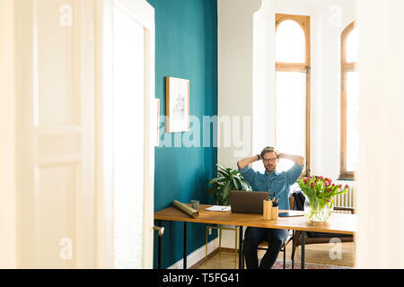 Casual businessman in home office working at his laptop Stock Photo