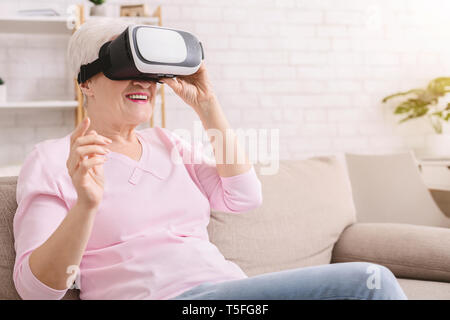 Senior woman watching video via vr glasses Stock Photo