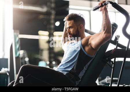 Young man exercising with training apparatus in gym, empty space Stock Photo