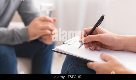 Psychologist taking notes during session with patient Stock Photo