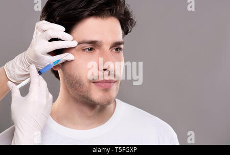 Millennial guy getting surgery filling of facial wrinkles Stock Photo