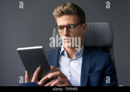 Young businessman sitting on office chair using tablet Stock Photo