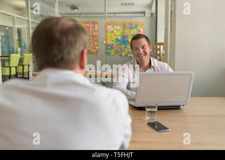 Two businessmen with laptop talking in office Stock Photo