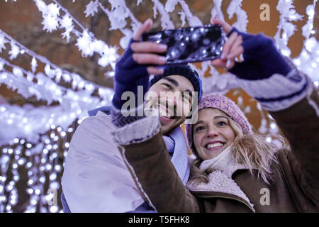 Happy young couple in winter decoration taking a selfie Stock Photo