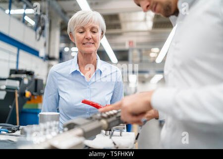 Businessman and senior businesswoman examining workpiece in a factory Stock Photo