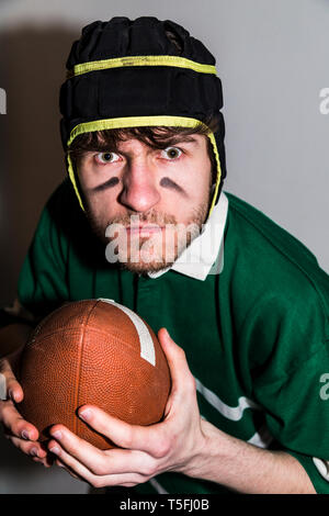Rugby player holding ball in hand and making faces Stock Photo