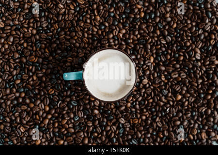 Cup of white coffee between coffee beans Stock Photo