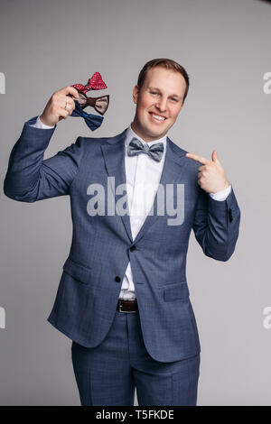 Smiling man insmart suit keeping bow ties in hand Stock Photo