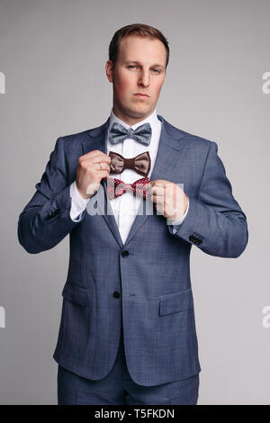 Smiling man insmart suit keeping bow ties in hand Stock Photo