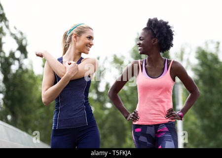 Two sporty young women talking and relaxing after running in the city Stock Photo