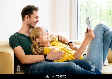 Couple sitting on couch in their new home, using digital tablet Stock Photo