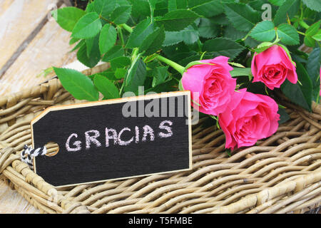 Gracias (thank you in Spanish) card with pink wild roses on wicker tray Stock Photo