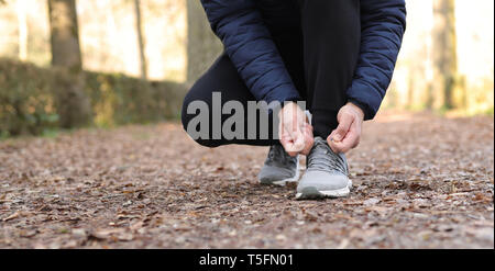 Man tying laces of running shoes before training. Stock Photo