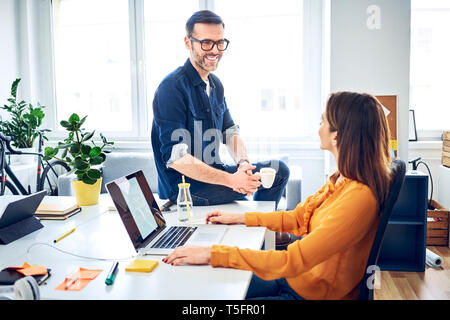 Two colleagues talking at desk in office Stock Photo