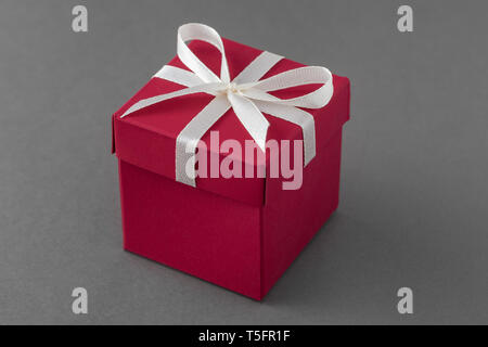 Red luxury gift box with ribbon on gray background. Stock Photo