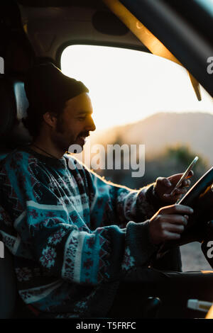 Young man on a road trip, using smartphone Stock Photo