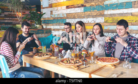 Social media addiction concept with young people photographing food at modern pub Stock Photo