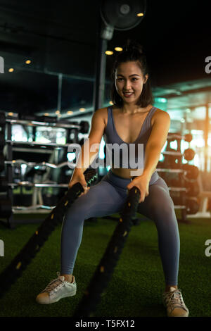 Woman with battle rope battle ropes exercise in the fitness gym. exercises concept. healthy concept heavy exercise in gym fitness. Stock Photo