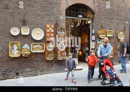 SIENA, ITALY - MAY 3, 2015: Tourists walk by souvenir shop in Siena, Italy. Siena as a UNESCO World Heritage Site is an important tourism destination  Stock Photo