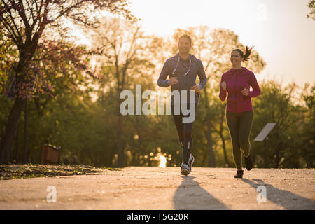 Running young couple in shadows with sun light behind them while