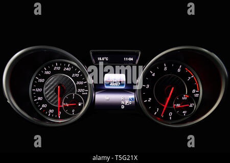 The dashboard of the car is glowing blue with red arrows at night with a speedometer, tachometer and other tools to monitor the condition of the vehic Stock Photo