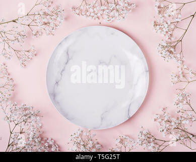 Romantic table setting in pink colors. Light pastel pink background with white flowers frame. Stock Photo
