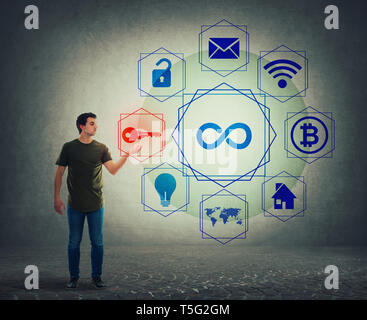 Young man holding a magic private key in hand choosing a icon from digital screen hologram interface. Modern technology concept, infinite virtual serv Stock Photo