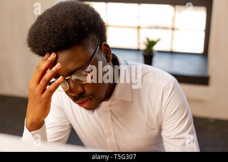 Serious nice young man touching his forehead Stock Photo