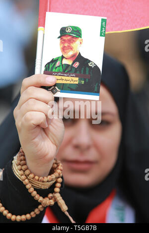 Baghdad, Iraq. 24th Apr, 2019. A woman holding a picture of a deceased Iranian fighter attends a conference organized by the predominantly Shia Muslim Popular Mobilization Forces (PMF) to honour Iranian fighters who died fighting the so-called Islamic State (IS) terror group. Credit: Ameer Al Mohammedaw/dpa/Alamy Live News Stock Photo