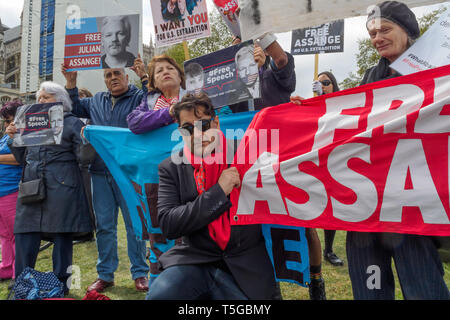 London, UK. 24th Apr, 2019. Afshin Rattansi from RT's 'Going Underground' programme poses with protesters in Parliament Square calling for the release of Julian Assange. They say he should not be extradited to the US as once there he will be charged with more serious crimes and locked away for life as a deterrent to other whistleblowers. Speakers included Human Rights activist Peter Tatchell and Afshin Rattansi from RT's 'Going Underground' news programme. Credit: Peter Marshall/Alamy Live News Stock Photo