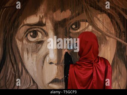 April 24, 2019 - Gaza City, The Gaza Strip, Palestine - A Palestinian girl takes a photo during 'Dreamers Among The Rubble' exhibition in Gaza city, a painting exhibition on the remains of the Italy tower walls, Italy tower destroyed by an Israeli airstrike overnight in Gaza City on August 26, 2014. (Credit Image: © Abed Alrahman Alkahlout/Quds Net News via ZUMA Wire) Stock Photo