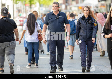 Nuremberg, Germany. 25th Apr, 2019. Nadine Grünbaum and Raine Zuber, both members of the Bavarian Security Guard, walk through the pedestrian zone in their new clothes and equipment. The volunteers receive neon yellow warning vests, flashlights and an improved pepper spray for their 25th anniversary. The new dark blue clothing of the security guard is modelled on the current Bavarian police uniforms. Credit: Daniel Karmann/dpa/Alamy Live News Stock Photo