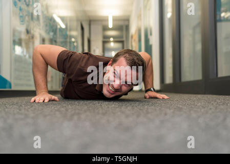 Businessman doing push-ups on office floor Stock Photo