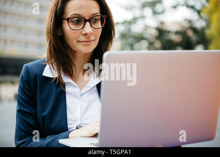 Businesswoman in the city using laptop Stock Photo