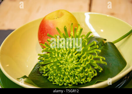 Table setting with plate of apple and a beautiful green flower Stock Photo