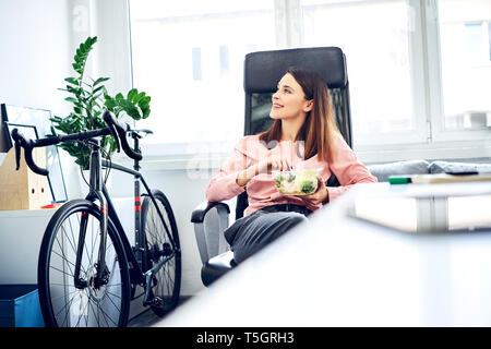 Businesswoman having lunch break in office sitting at desk Stock Photo