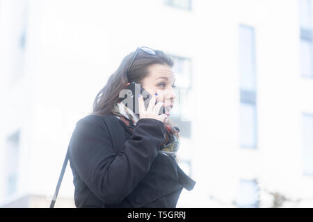 Surprised young woman on the phone Stock Photo