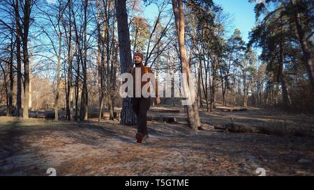 Active male portrait of caucasian sporty man guy hiking outdoors in pine forest. young man tourist with beard and bandage, bandana on his head wearing Stock Photo