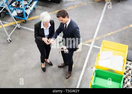 Businessman and senior businesswoman examining workpiece in a factory Stock Photo