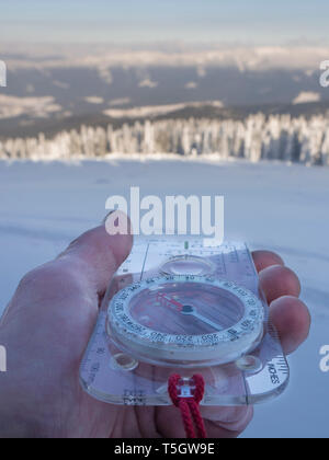 Germany, Upper Bavarian Forest Nature Park, man's hand holding compass in winter Stock Photo