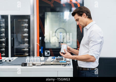 Businessman examining workpiece in a factory Stock Photo