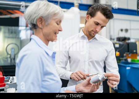 Businessman and senior businesswoman examining workpiece in a factory Stock Photo