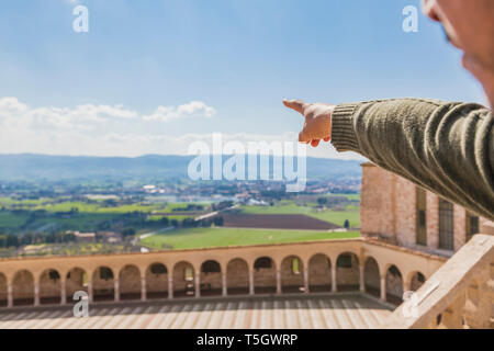 Italy, Umbria, Assisi, man's hand pointing at the fields surrounding the Basilica of San Francesco d'Assisi Stock Photo