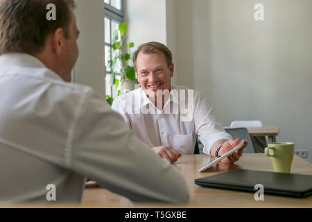 Two businessmen working with tablet in office Stock Photo