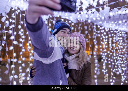 Happy young couple in winter decoration taking a selfie Stock Photo