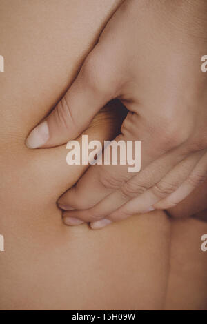 Close view of woman hands squeezing skin on leg for checking cellulite. Stock Photo