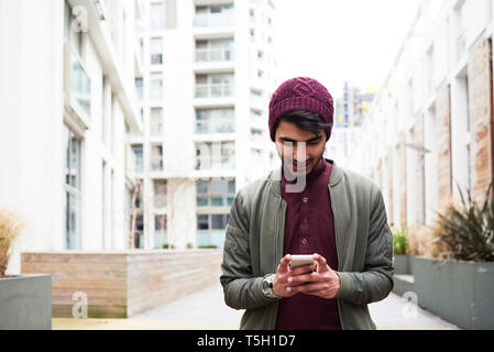 Portrait of cheerful bearded man in purple hat using his mobile phone Stock Photo