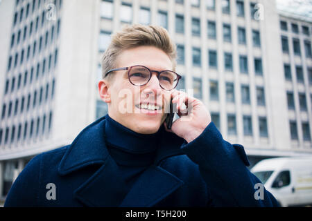 Portrait of smiling young man talking on cell phone in the city Stock Photo