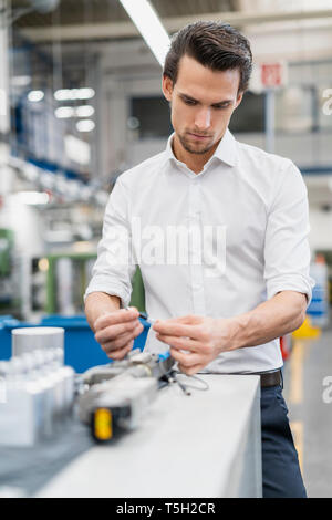 Businessman examining workpiece in a factory Stock Photo