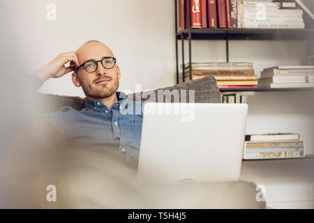 Man sitting on couch, usinag laptop Stock Photo